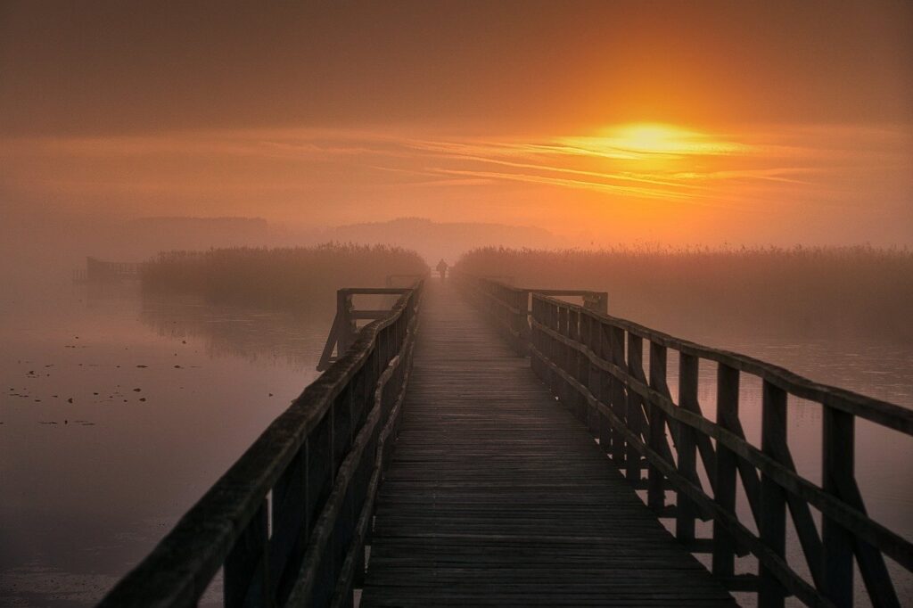 Steg über nebliges Wasser bei Sonnenaufgang – symbolisiert einen Weg zu neuer Klarheit, innerer Ruhe und Selbstentdeckung.